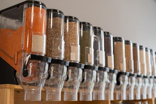 A woman fills a jar with red lentils. Selling bulk goods by weight in an eco store. Trade concept without plastic packaging.