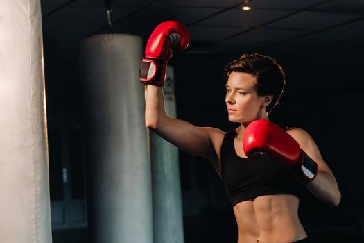 portrait of a female boxer in red gloves in the gym during training.