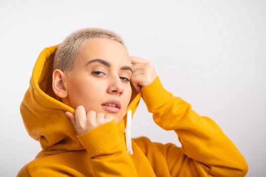 Young woman in an ocher hood on a white background