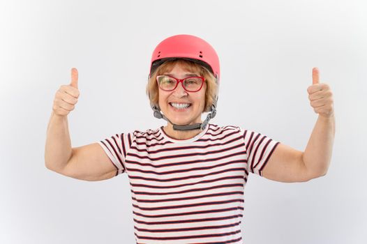 Elderly woman in ski helmet showing thumb up on white background