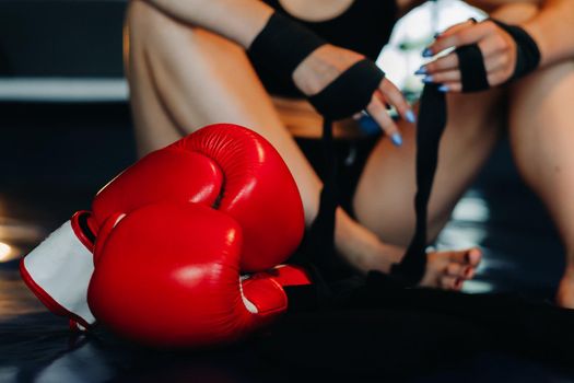 Close-up of red boxing gloves on the floor of a blue boxing ring.