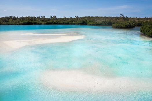 A view from a height of a Tropical beach and waves breaking on a tropical golden sandy beach. The sea waves gently wind along the beautiful sandy beach.