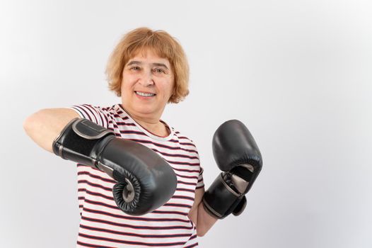 Elderly woman in fighting gloves in a defensive pose on a white background