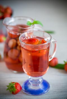 Sweet refreshing berry compote of ripe strawberries in a decanter on a wooden table