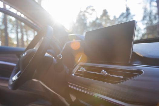 interior of modern luxury car in sunshine. monitor, airduct and steering wheel on premium car, side view, sunlight