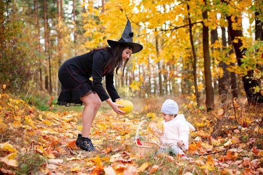 black witch woman with little toddler bunny in the autumn forest. halloween celebration, costume party.