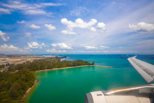 view of the tropical ocean coast from the porthole of a landing plane. holiday travel