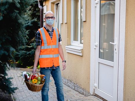 Volunteer work on food delivery during the coronavirus pandemic. Portrait of a man holding a basket of food.