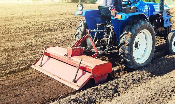 Farmer on a tractor cultivates land after harvesting. Development of agricultural technologies. Grinding loosening plowing crumbling soil for further sowing by cultivated plants. Milling machine