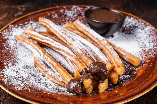 Spanish tapas churros with sugar and chocolate sauce. Dark background. Top view.
