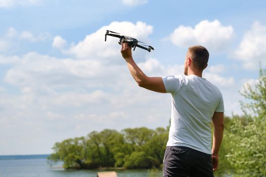 A man with a flying vehicle in his hands, raised to the sky in nature.Launching a drone.