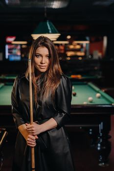 A girl with a cue in her hands is standing in a billiard club.Russian billiards.