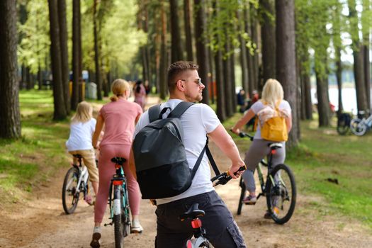 A group of cyclists with backpacks ride bicycles on a forest road enjoying nature.