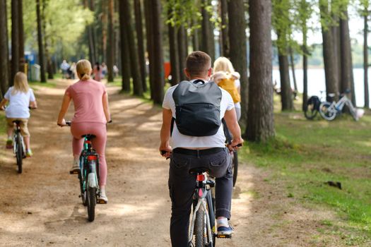 A group of cyclists with backpacks ride bicycles on a forest road enjoying nature.