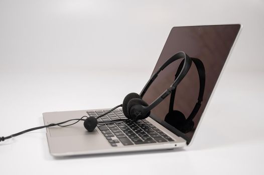 Headset on laptop keyboard on white background