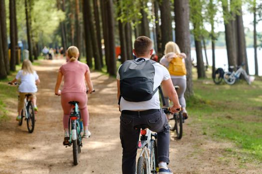 A group of cyclists with backpacks ride bicycles on a forest road enjoying nature.