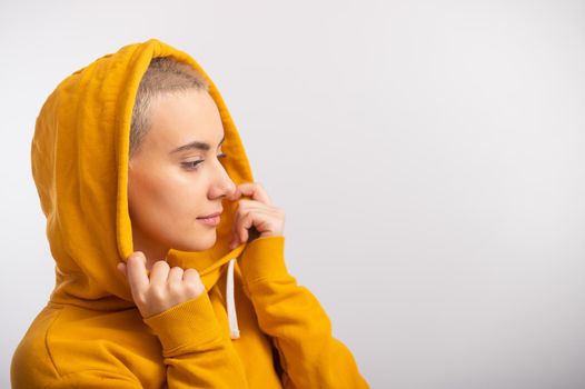 Young woman in an ocher hood on a white background