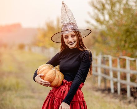 halloween portrait of teenage girl in witch hat with pumpkin