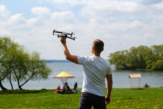 A man with a flying vehicle in his hands, raised to the sky in nature.Launching a drone.