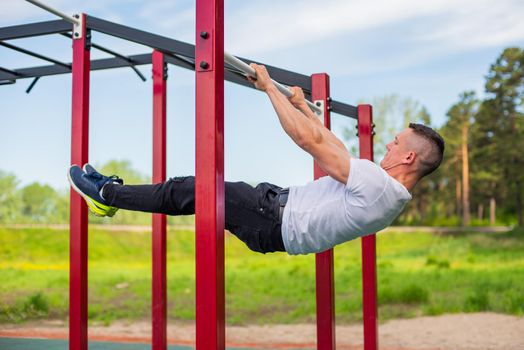 Caucasian man doing a back plank on the uneven bars. Workout on the sports ground