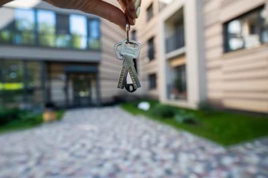 A woman holds the keys to a new house. Close-up of a female hand. Buying a property