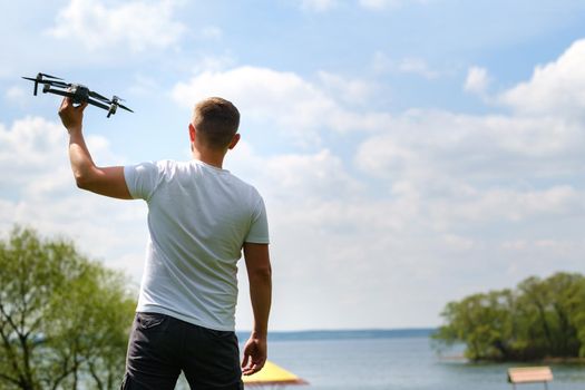 A man with a flying vehicle in his hands, raised to the sky in nature.Launching a drone.