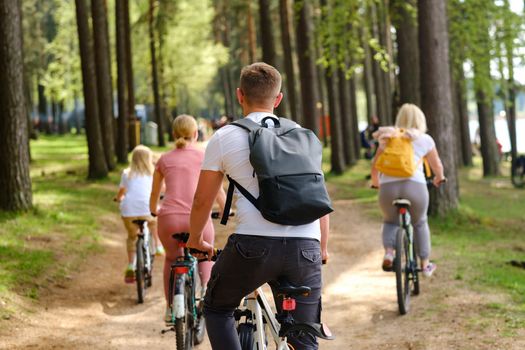 A group of cyclists with backpacks ride bicycles on a forest road enjoying nature.