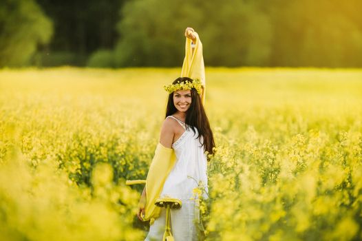 a woman enjoys a bike ride in a field full of bright yellow rapeseed.