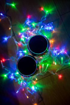 top view of glass wine glasses in shining christmas garland on dark background....
