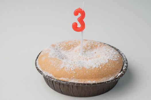 small cake with a candle in the shape of the number three for birthday