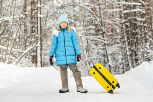 A girl in winter in felt boots goes with a suitcase on a frosty snowy day.