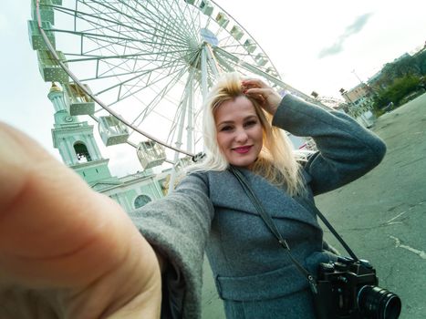 The young girl walks around the city near sights. Ferris wheel. Amusement park. autumn