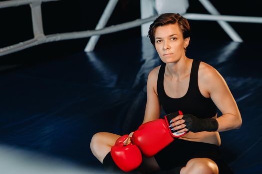 portrait of a female boxer in red gloves in the gym after training.