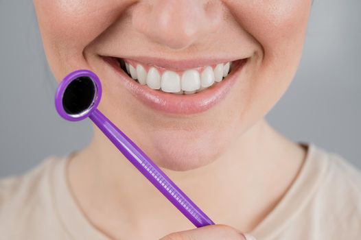 Caucasian woman with snow white smile holding dentist mirror