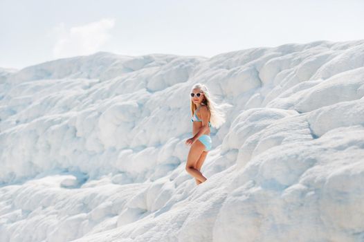 Girl in a swimsuit and sunglasses on White mountain, Sunny day, Pamukkale Turkey.