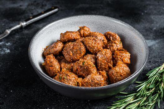 Roasted Meatballs in tomato sauce from ground beef and pork meat with rosemary. Black background. Top view.