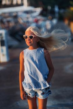 Portrait of a cute smiling ten-year-old girl with glasses.A girl in shorts and a blue t-shirt at sunset near the sea.Turkey