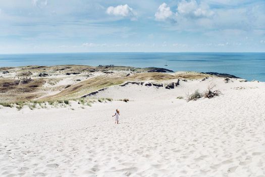 a child has fun in the sand dunes on the beach in Nida.Lithuania.