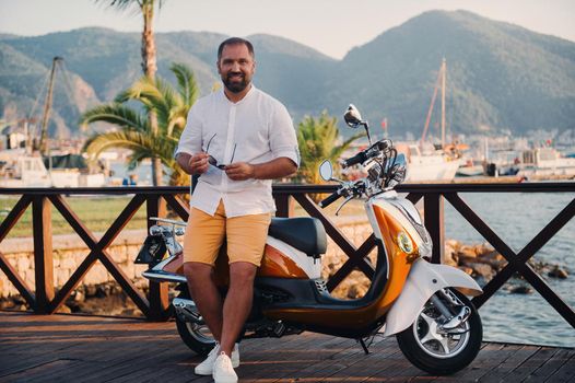 Portrait of a free happy man with scooters near the sea.Recreation, Travel on a scooter