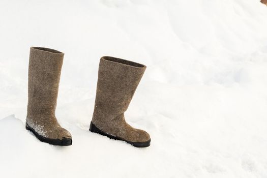 close up of felt boots standing in the snow.