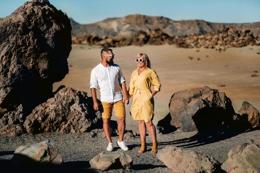 a couple, a woman and a man in the desert crater of the Teide volcano and enjoy the sunset view. Travel to the mountains, freedom and the concept of an active lifestyle.Canary Islands, Spain.