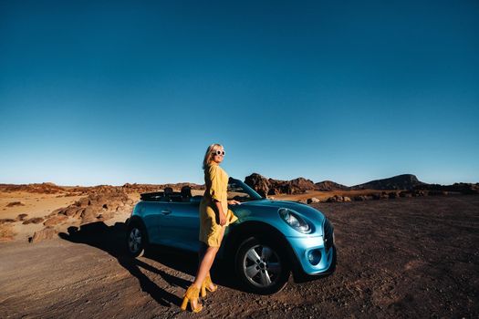 Woman enjoying road trip, standing with map near convertible car on the roadside in the volcanic mountain forest on Tenerife island, Spain