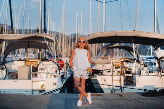 Portrait of a stylish girl near the sea in a yacht club. Girl on the pier near the yacht Parking lot.