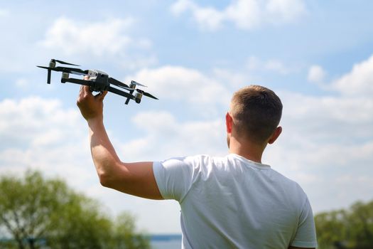 A man with a flying vehicle in his hands, raised to the sky in nature.Launching a drone.