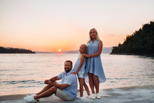 beautiful family walks on the pier near the sea at sunset