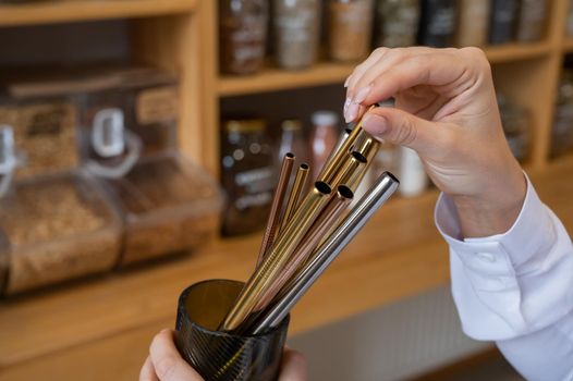 A woman holds a jar of reusable steel tubes. Eco concept.