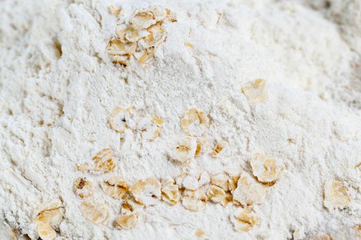 white wheat flour with oat flakes, close-up photo on wooden surface