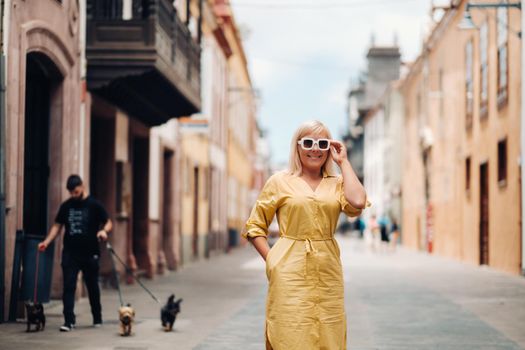 a blonde woman in a yellow summer dress stands on the street of the Old town of La Laguna on the island of Tenerife.Spain, Canary Islands.