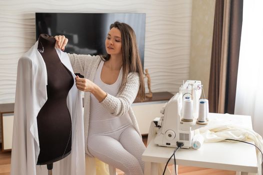 Caucasian woman sews to order at home. Work space of a seamstress in the living room.