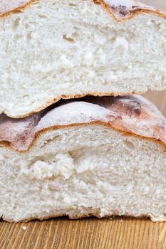 Two half freshly baked wheat bread, lying on top of each other. Photo close-up of half loaf on a wooden surface